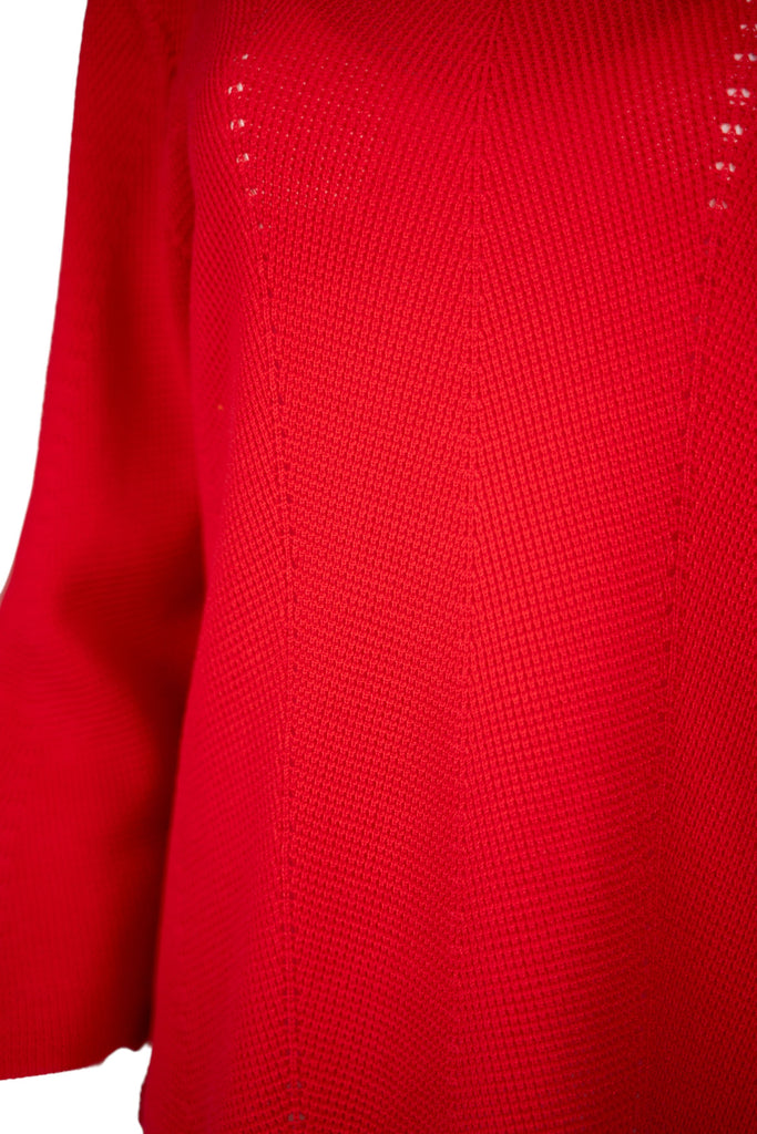 Detailansicht Strick - Damenpullover in leuchtendem Rot mit Rundhalsausschnitt und langen Ärmeln. Der Feinstrick zeigt ein dezentes Lochmuster in vertikaler Linie – modisch und luftig zugleich.