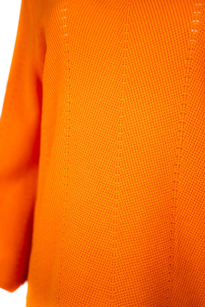 Detailansicht Strick - Damenpullover in leuchtendem Orange mit Rundhalsausschnitt und langen Ärmeln. Der Feinstrick zeigt ein dezentes Lochmuster in vertikaler Linie – modisch und luftig zugleich.