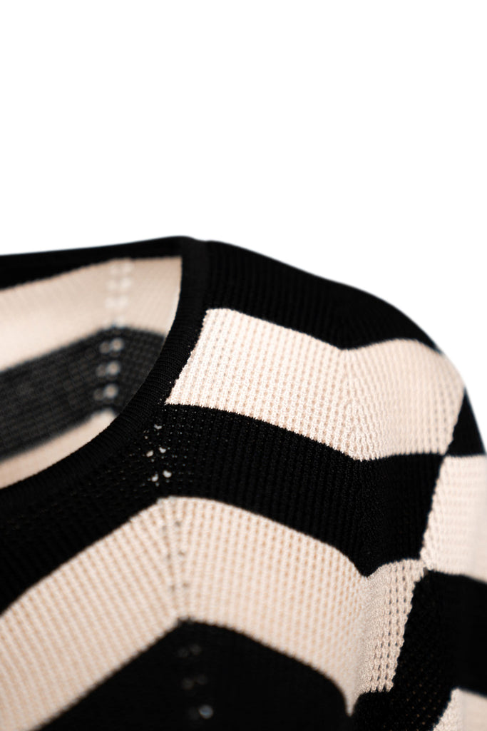 Detailansicht Schulter - Damen-Strickjacke mit offenem Frontbereich und kleinem Hakenverschluss am Rundhalsausschnitt, 3/4-Ärmeln und breitem Zickzackringelmuster in Schwarz und Beige.