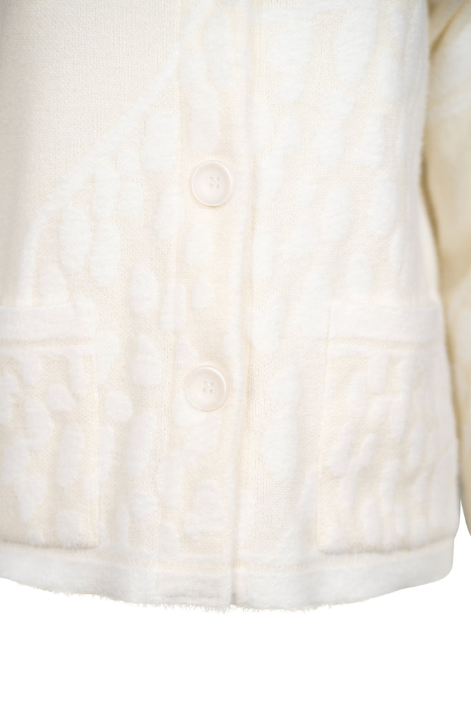 Detailansicht Knopfleiste - Cremefarbene Strickjacke mit Stehkragen, durchgehender Knopfleiste und aufgesetzten Taschen. Strukturierte Strickmuster sorgen für einen hochwertigen, gemütlichen Look – ideal für kühle Tage.