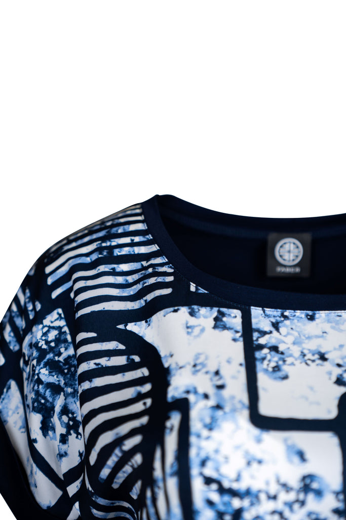 Detailansicht Kragen - Kurzärmeliges Damen-Shirt mit abstraktem, blau-weißem Muster und schwarzen Linien. Der Rundhalsausschnitt und die Ärmelabschlüsse sind in Dunkelblau eingefasst. Ideal für einen modernen Freizeitlook.