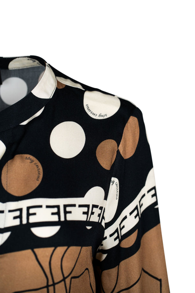 Detailansicht Schulter - Langärmlige Bluse mit vielfältigem Mustermix in Schwarz, Braun und Weiß. Die Bluse kombiniert Punkte, Linienzeichnungen und grafische Elemente, hat einen kleinen Stehkragen, V-Ausschnitt sowie einen Tunnelzug am Saum für variablen Sitz.
