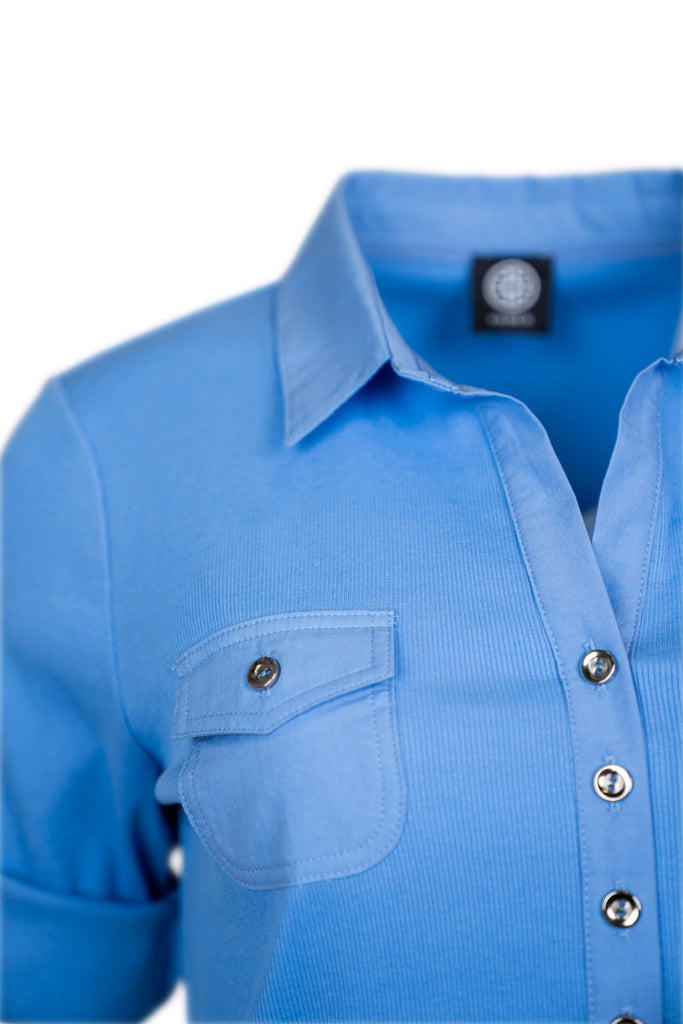 Detailansicht Kragen - Blaues Damen-Poloshirt mit halber Knopfleiste und kurzen, aufkrempelbaren Ärmeln. Zwei Brusttaschen mit Knopfklappen. Innenkragen mit rot-weißem Muster als farbiger Akzent. Sportlich und stilvoll zugleich.