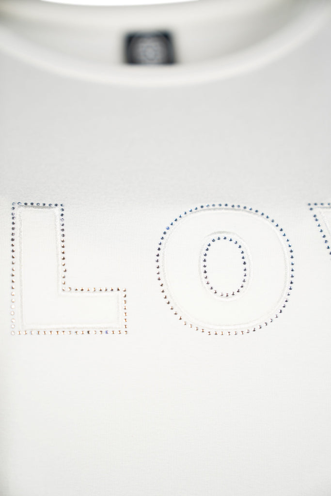 Detailansicht der Aufschrift - Lockeres Damen-T-Shirt in weiß mit Rundhalsausschnitt und dem Schriftzug „SLOW“.