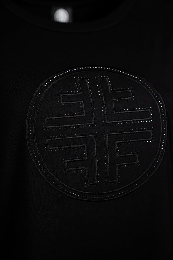 Detailansicht Logo - Schwarzes Damen-T-Shirt mit Rundhalsausschnitt und halblangen Ärmeln. Auf der Vorderseite befindet sich ein dezentes, schwarzes, kreisförmiges Faber-Logo in Ton-in-Ton-Optik mit leicht glänzender Struktur – minimalistisch und stilvoll zugleich.